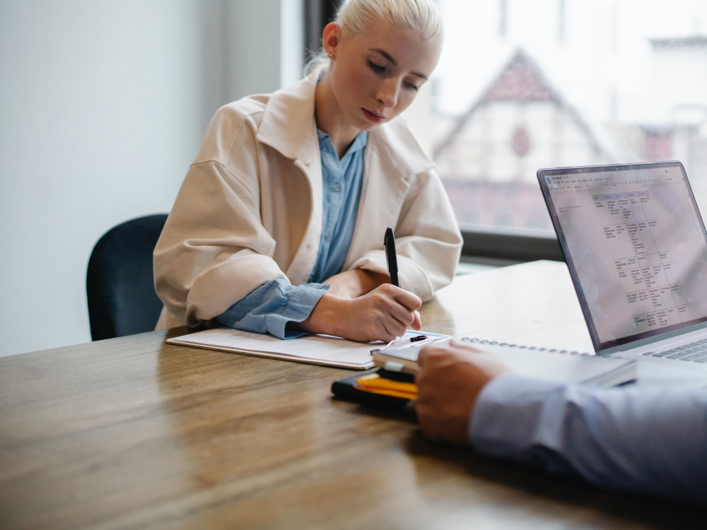 Woman signing documents while sitting at a table